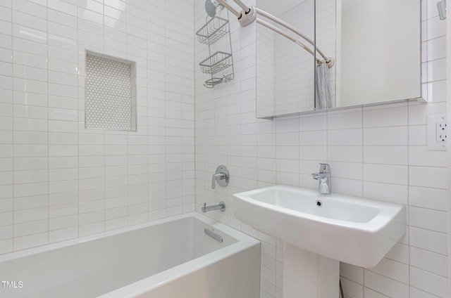 bathroom featuring tile walls, shower / tub combo with curtain, and a sink