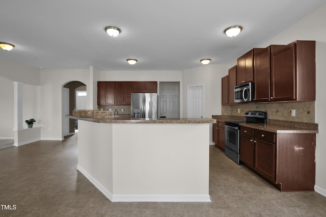5824 Lady Way, Hope Mills, NC 28348 - kitchen with baseboards, a kitchen island with sink, stainless steel appliances, tasteful backsplash, and arched walkways