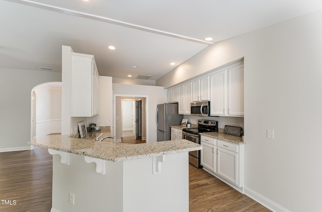 315 Copper Ridge Dr, Sanford, NC 27330 - kitchen featuring dark wood-style flooring, stainless steel appliances, a kitchen breakfast bar, a peninsula, and arched walkways