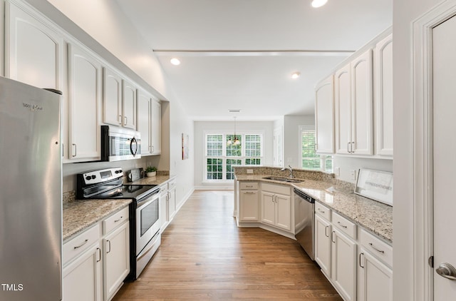 315 Copper Ridge Dr, Sanford, NC 27330 - kitchen with white cabinets, a sink, stainless steel appliances, light wood finished floors, and a peninsula