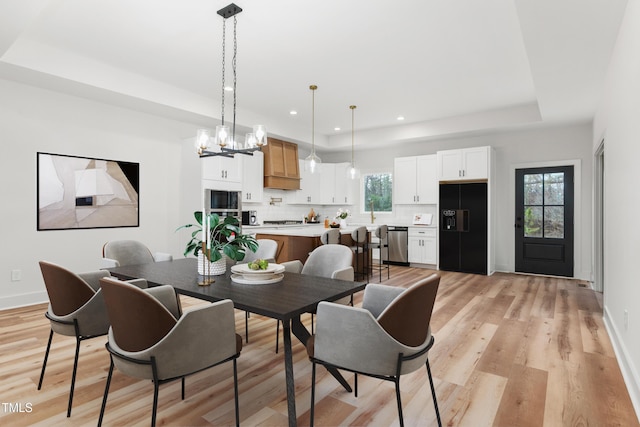 dining room with baseboards, a tray ceiling, recessed lighting, and light wood finished floors