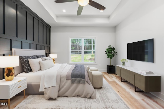 bedroom featuring a raised ceiling, light wood-type flooring, baseboards, ceiling fan, and recessed lighting