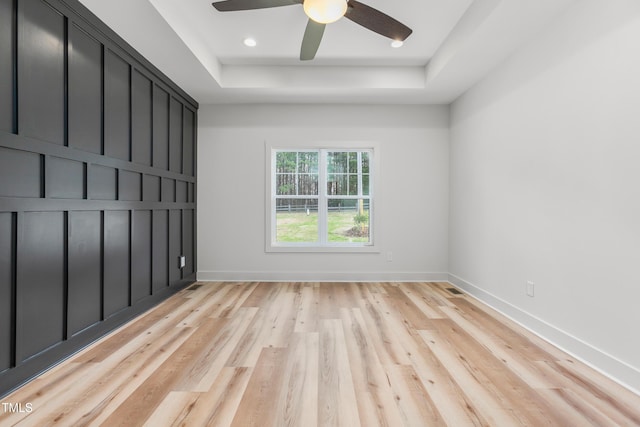 empty room featuring baseboards, ceiling fan, recessed lighting, a raised ceiling, and light wood-type flooring