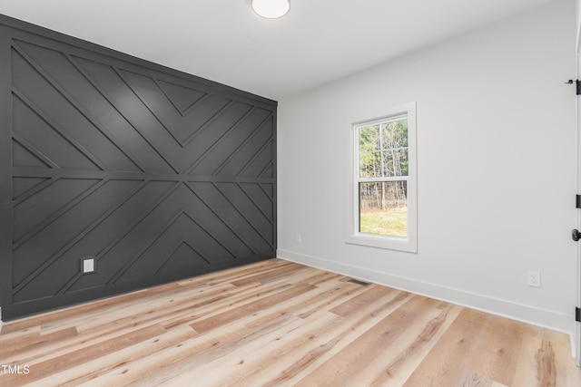 unfurnished room featuring baseboards, visible vents, and wood finished floors