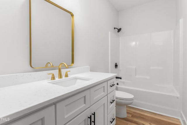 bathroom with washtub / shower combination, toilet, wood finished floors, and vanity