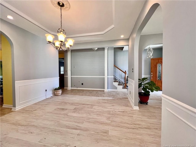 unfurnished dining area featuring a raised ceiling, arched walkways, and an inviting chandelier