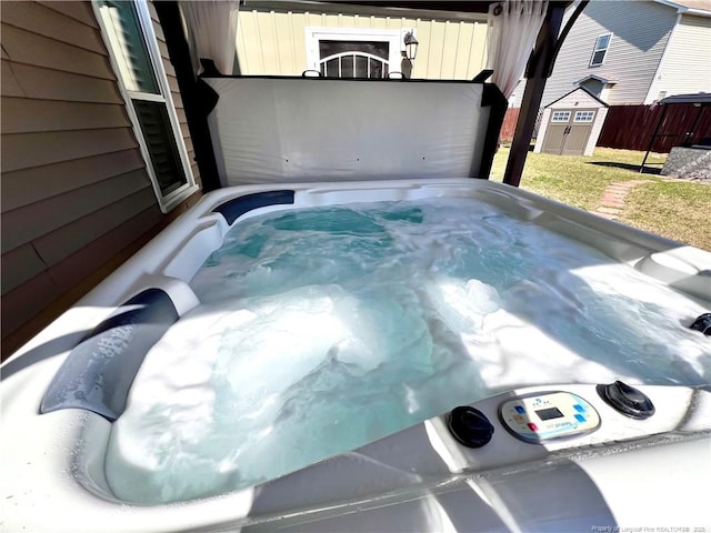 view of pool featuring a storage shed, an outdoor structure, fence, and a hot tub