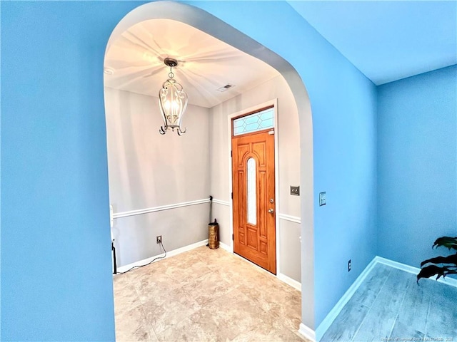 entrance foyer featuring visible vents, baseboards, arched walkways, and an inviting chandelier