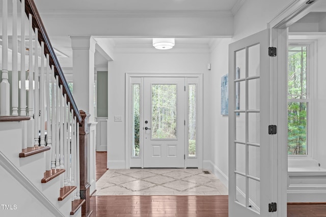 entryway featuring crown molding, a healthy amount of sunlight, hardwood / wood-style flooring, and stairs