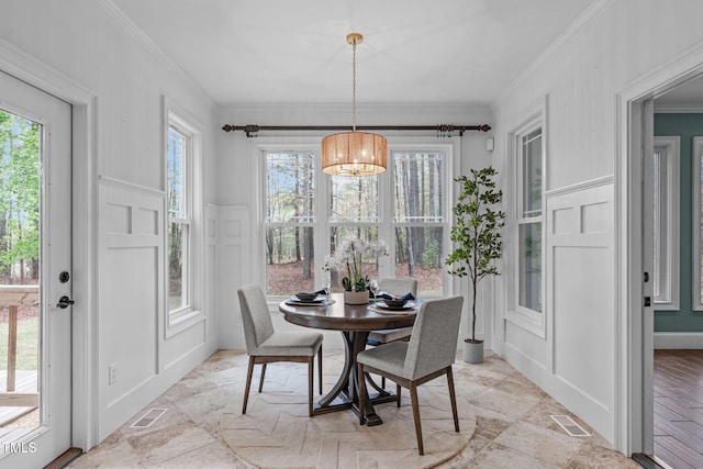 dining space with a decorative wall, ornamental molding, visible vents, and stone tile flooring
