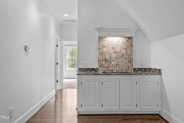kitchen featuring dark stone counters, dark wood finished floors, tasteful backsplash, visible vents, and baseboards