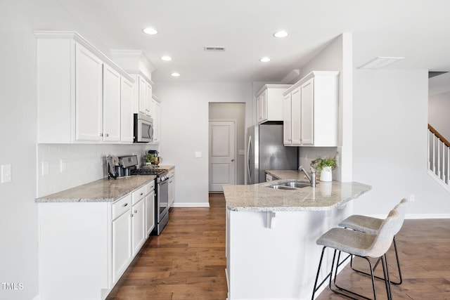 122 Torpoint Rd, Durham, NC 27703 - kitchen with stainless steel appliances, a peninsula, a breakfast bar area, recessed lighting, and white cabinetry
