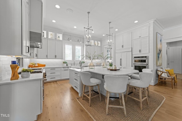 1208 Hunting Ridge Rd, Raleigh, NC 27615 - kitchen with light countertops, white cabinets, a breakfast bar area, a sink, and an island with sink