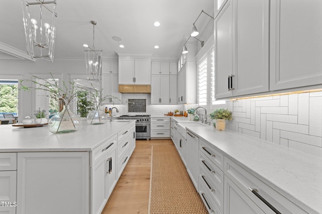 1208 Hunting Ridge Rd, Raleigh, NC 27615 - kitchen featuring a sink, stainless steel range, backsplash, light wood-type flooring, and white cabinetry