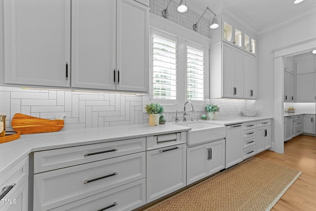 1208 Hunting Ridge Rd, Raleigh, NC 27615 - kitchen with a sink, tasteful backsplash, light countertops, light wood-style flooring, and ornamental molding