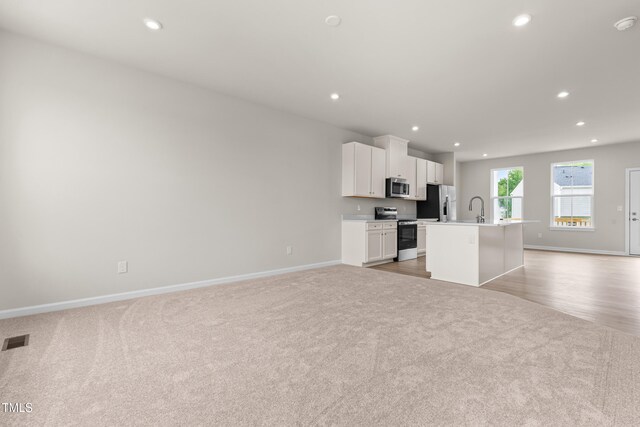 605 Silverado Sunset Loop, Wendell, NC 27591 - kitchen with appliances with stainless steel finishes, light carpet, open floor plan, a center island with sink, and recessed lighting
