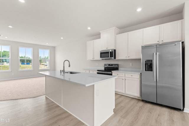 605 Silverado Sunset Loop, Wendell, NC 27591 - kitchen featuring appliances with stainless steel finishes, a sink, light wood finished floors, white cabinets, and a kitchen island with sink