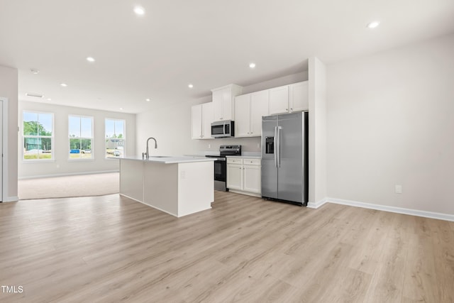 605 Silverado Sunset Loop, Wendell, NC 27591 - kitchen featuring stainless steel appliances, open floor plan, a center island with sink, light wood-style floors, and white cabinets