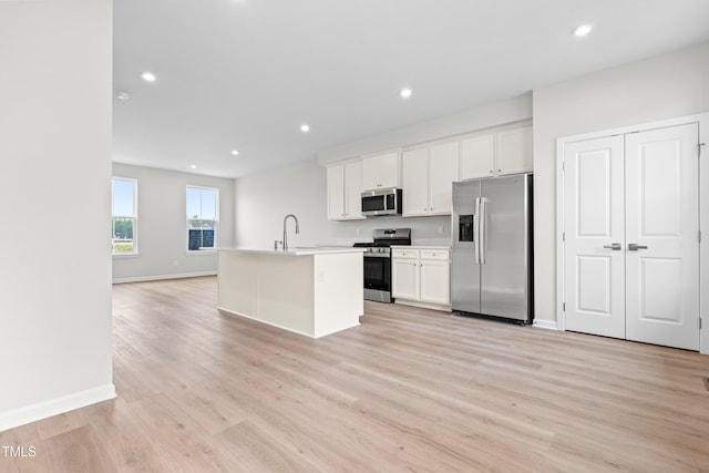 609 Silverado Sunset Loop, Wendell, NC 27591 - kitchen with appliances with stainless steel finishes, light wood-type flooring, a center island with sink, white cabinetry, and recessed lighting