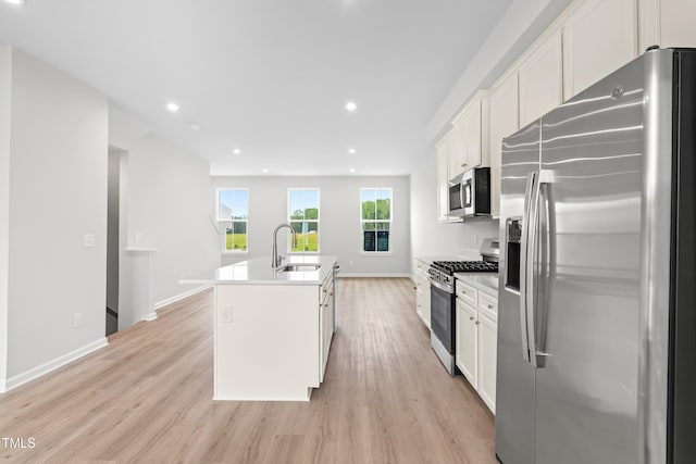 609 Silverado Sunset Loop, Wendell, NC 27591 - kitchen with stainless steel appliances, a sink, an island with sink, white cabinets, and light wood-style floors