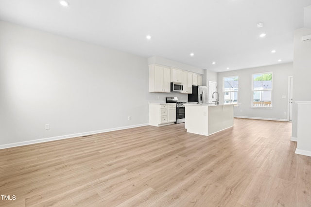 609 Silverado Sunset Loop, Wendell, NC 27591 - kitchen featuring appliances with stainless steel finishes, open floor plan, a kitchen island with sink, light wood-style floors, and recessed lighting