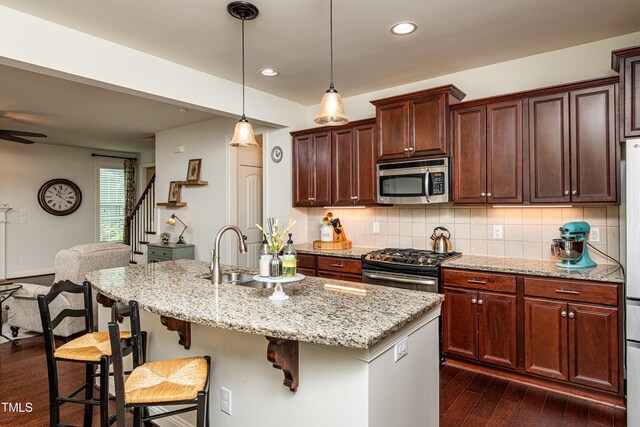 2739 Elderberry Ln, Apex, NC 27539 - kitchen with stainless steel appliances, a sink, dark wood-style flooring, tasteful backsplash, and a breakfast bar