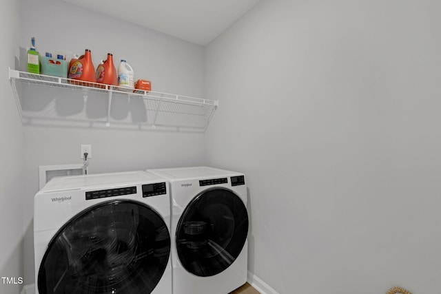 washroom featuring separate washer and dryer, baseboards, and laundry area