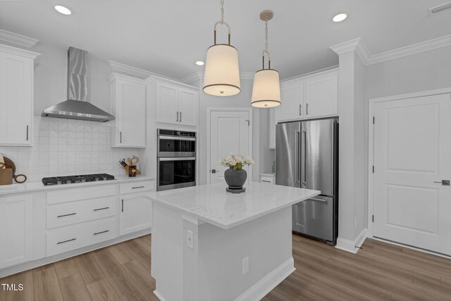 kitchen featuring visible vents, ornamental molding, wall chimney exhaust hood, stainless steel appliances, and white cabinetry