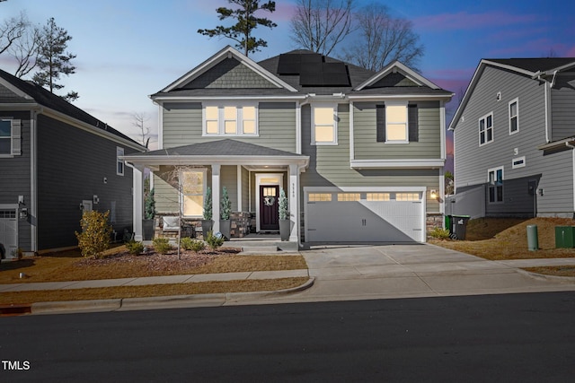 view of front of home with roof mounted solar panels, an attached garage, a porch, and concrete driveway