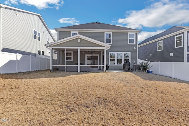 back of property featuring a lawn, a sunroom, and a fenced backyard
