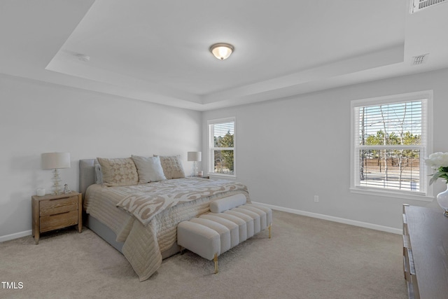 bedroom with baseboards, a tray ceiling, visible vents, and light colored carpet
