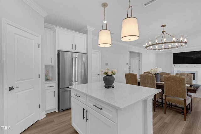kitchen with white cabinetry, crown molding, high end fridge, a chandelier, and light wood finished floors