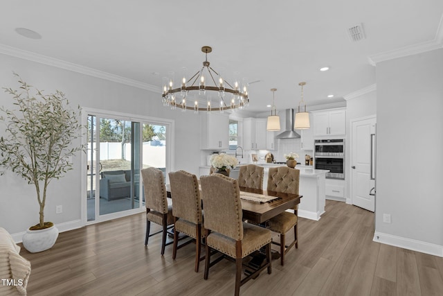dining room featuring a notable chandelier, wood finished floors, baseboards, visible vents, and ornamental molding