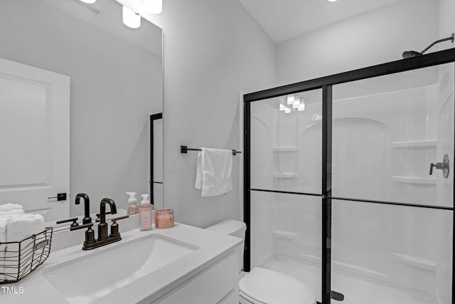 bathroom featuring toilet, vanity, and a shower stall