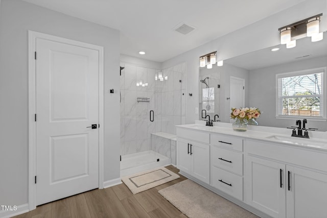 bathroom with a sink, a shower stall, visible vents, and wood finished floors