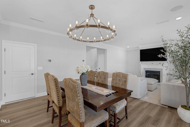 dining space with visible vents, ornamental molding, light wood-style flooring, and a notable chandelier