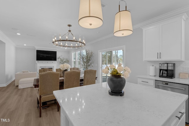 dining space with ornamental molding, baseboards, light wood finished floors, a notable chandelier, and a fireplace