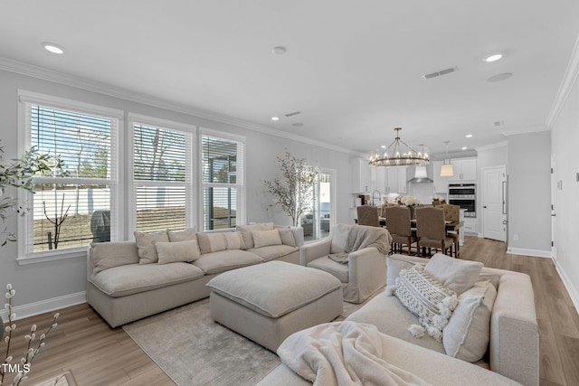 living area featuring visible vents, a notable chandelier, light wood-style floors, and ornamental molding