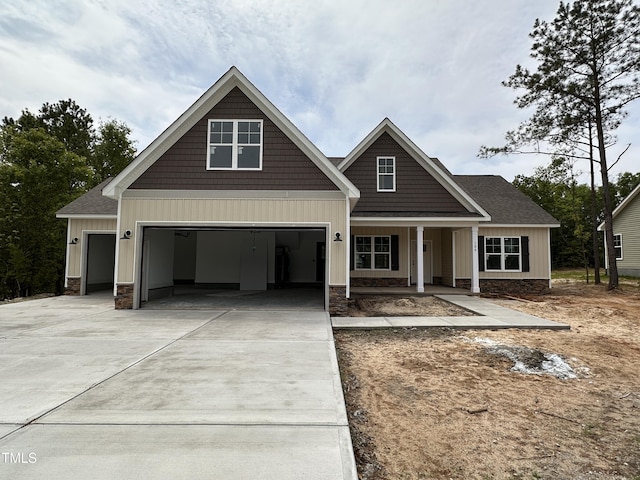 craftsman house with concrete driveway, a garage, covered porch, and roof with shingles