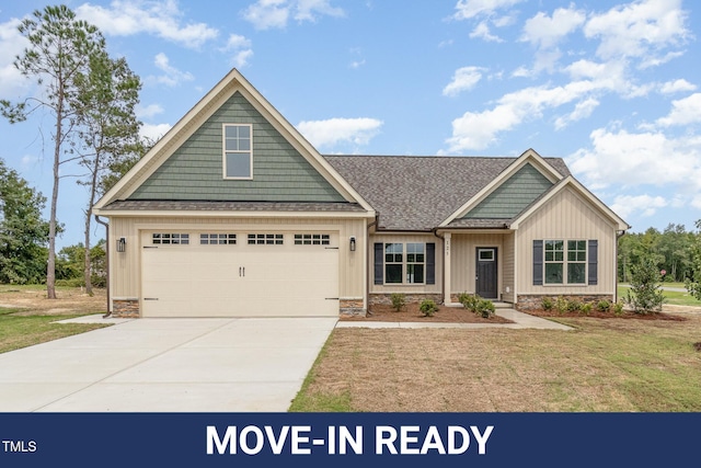 craftsman-style house with a front yard, a garage, board and batten siding, driveway, and roof with shingles