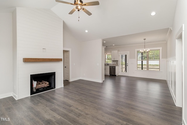 unfurnished living room with ceiling fan with notable chandelier, a large fireplace, recessed lighting, wainscoting, and dark wood-style floors