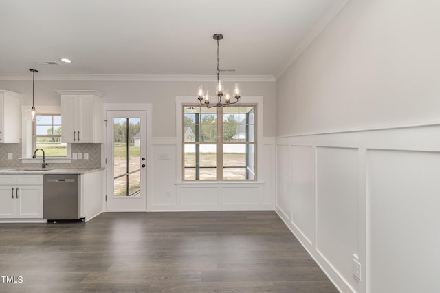 unfurnished dining area featuring a sink, an inviting chandelier, crown molding, and dark wood-type flooring
