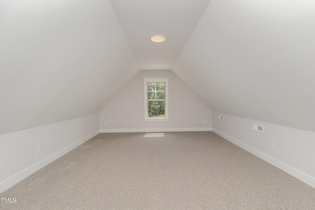 bonus room featuring visible vents, light colored carpet, baseboards, and lofted ceiling