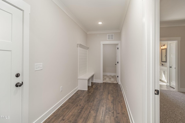hallway featuring crown molding, visible vents, baseboards, and dark wood-type flooring