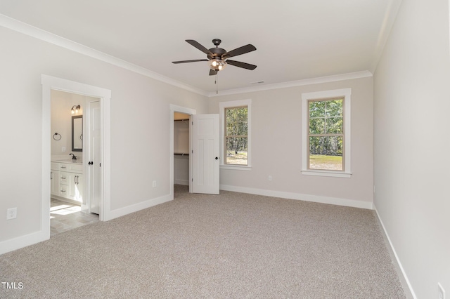 unfurnished bedroom featuring crown molding, a spacious closet, visible vents, light carpet, and baseboards