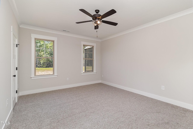 empty room featuring ceiling fan, baseboards, ornamental molding, and carpet floors