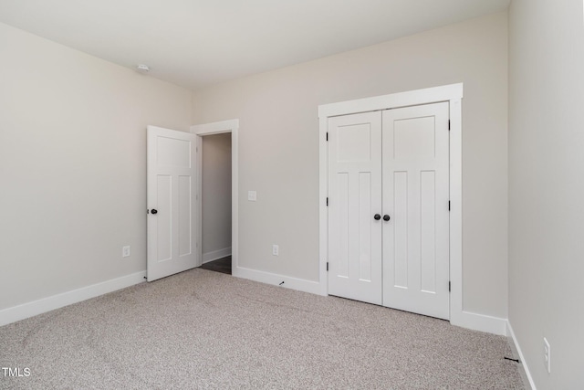 unfurnished bedroom with a closet, carpet flooring, and baseboards