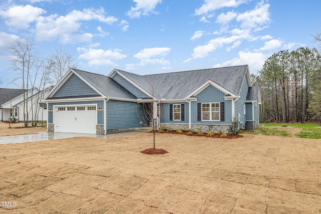 view of front of house featuring board and batten siding, central AC, stone siding, an attached garage, and concrete driveway
