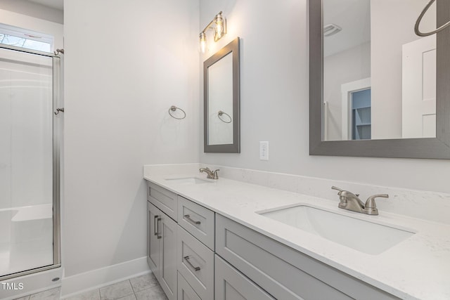 full bathroom with a shower, double vanity, baseboards, and a sink