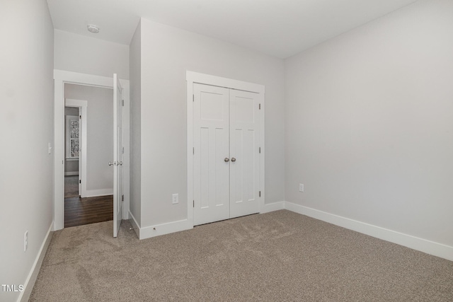 unfurnished bedroom with a closet, carpet, and baseboards